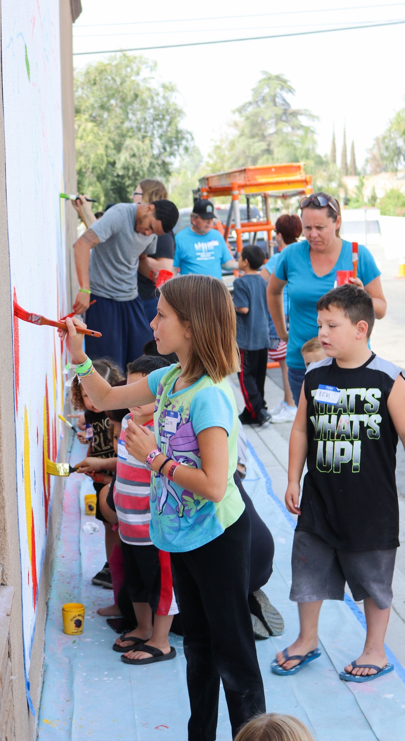 Little Girl and Other Children and Adults of the Community Work on Mural