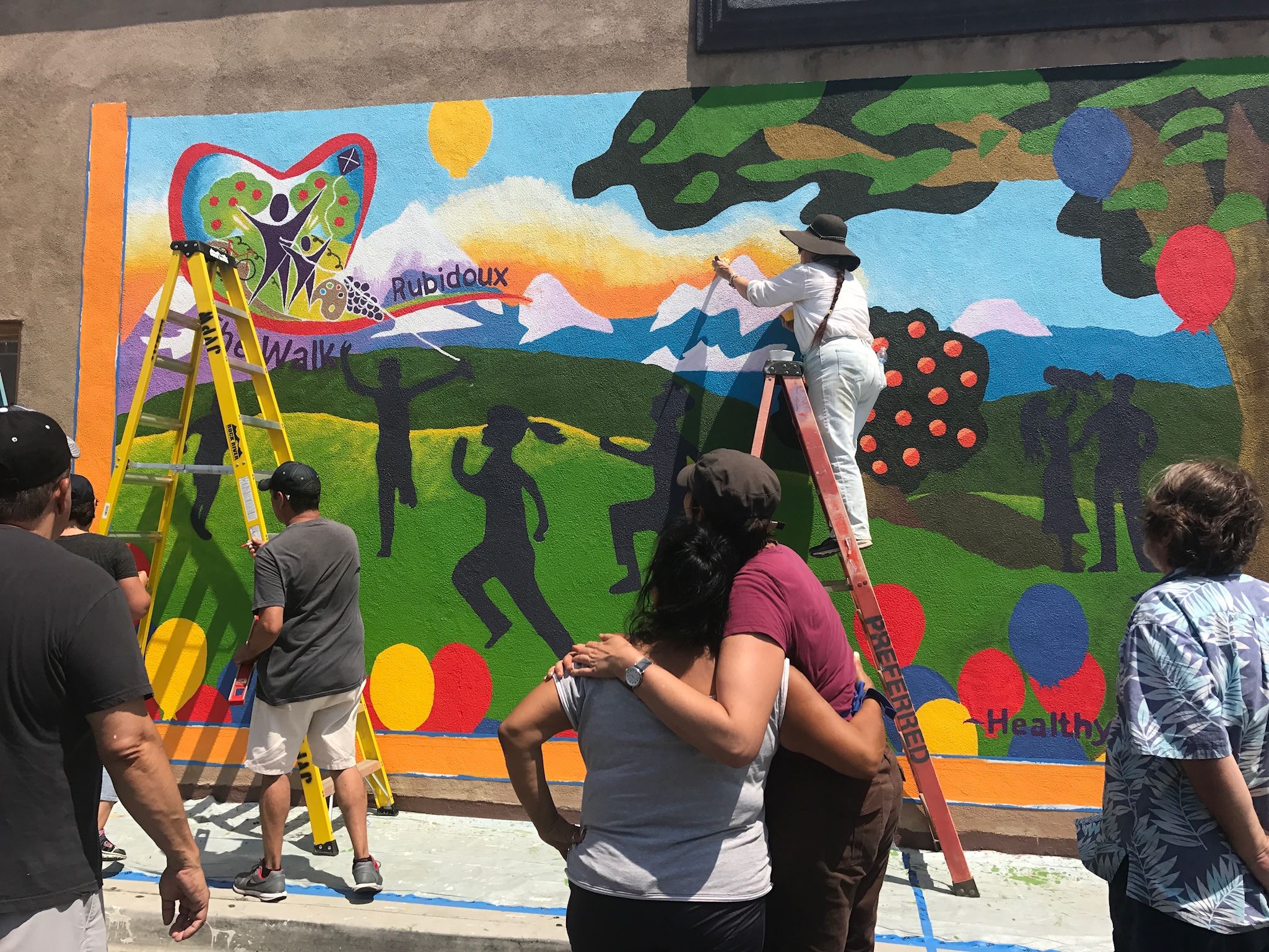 People Embrace in Front of Completed Mural