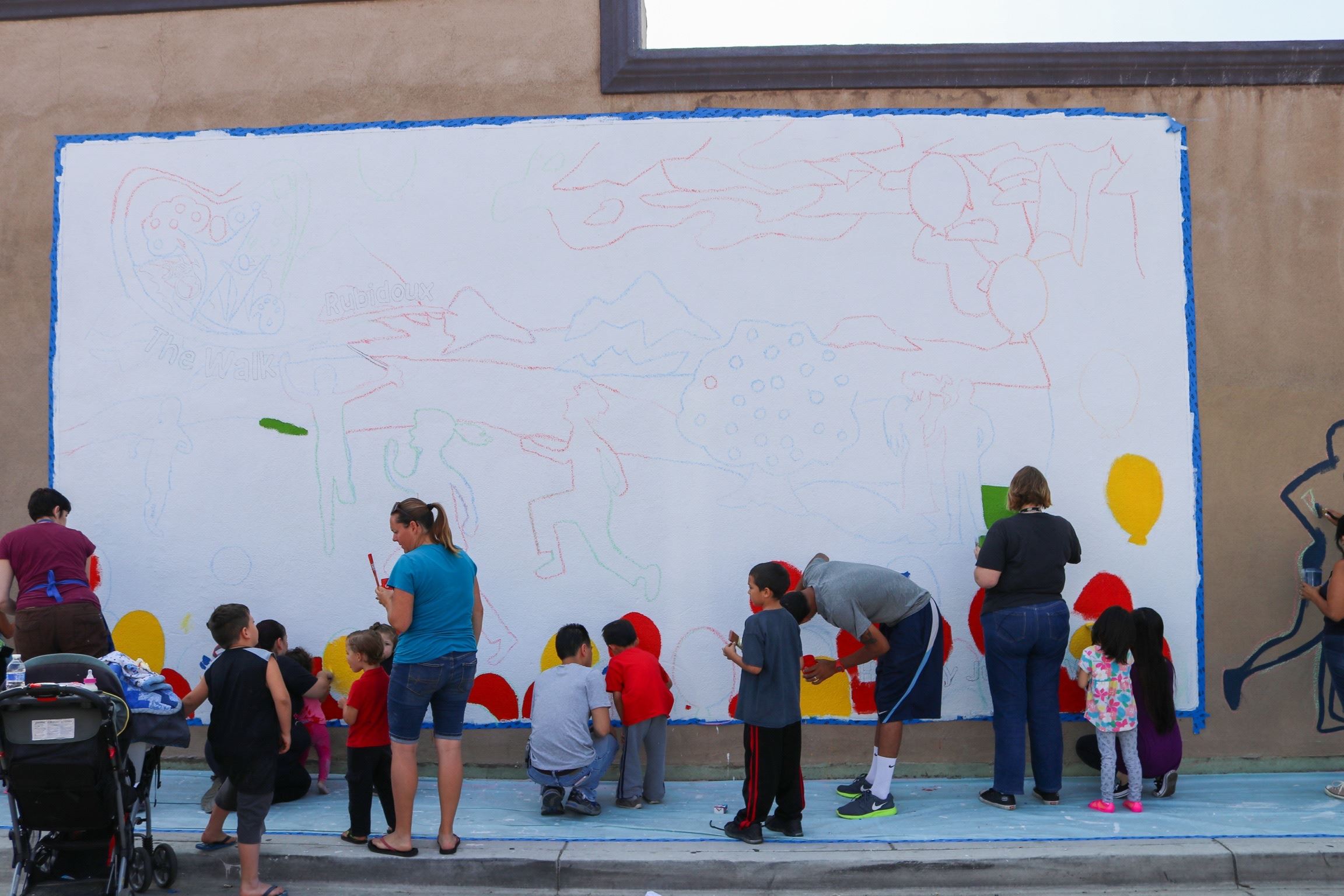 People Stand in Front of Outlined Mural